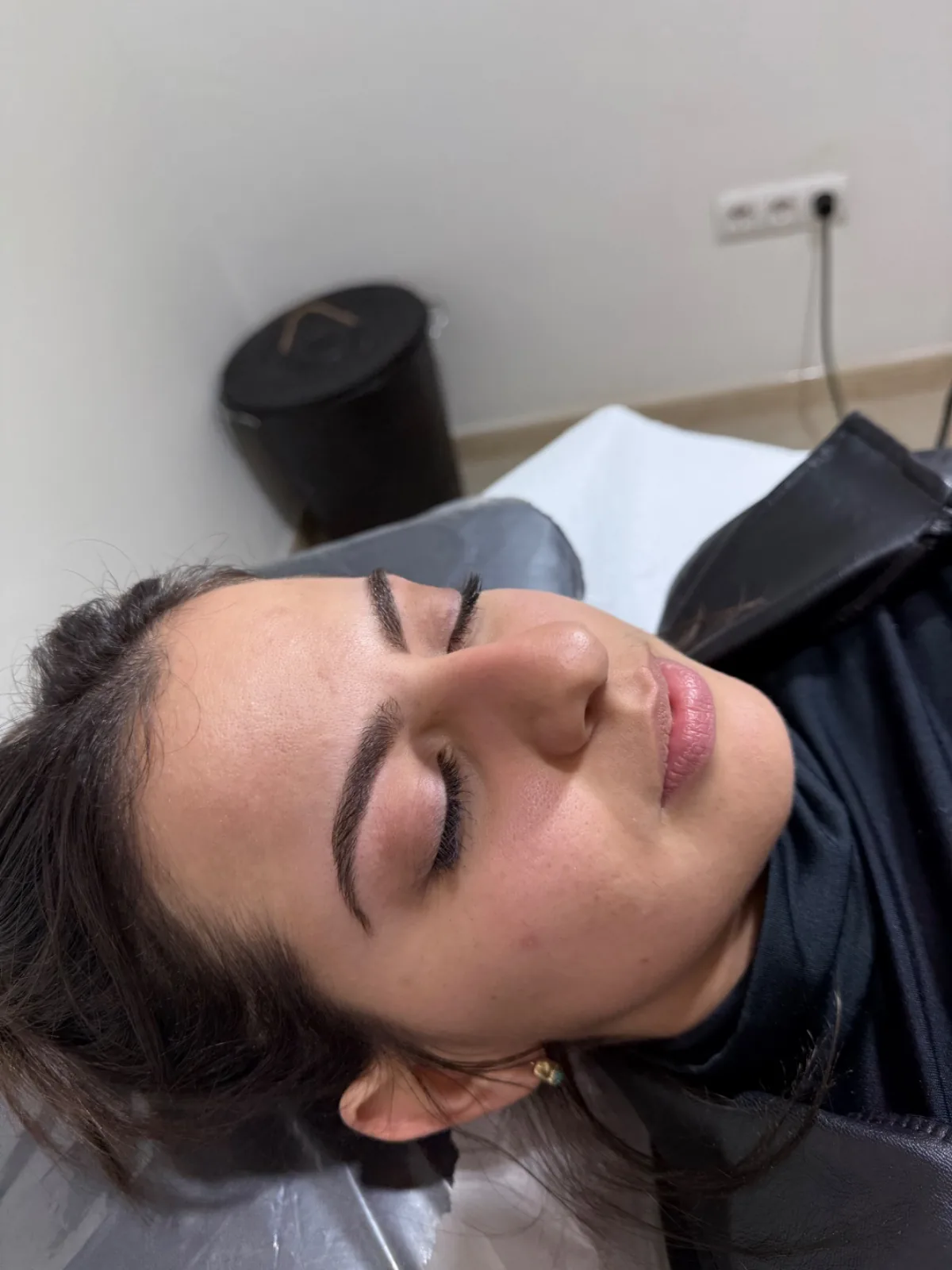Clienta tumbada en la camilla con pestañas levantadas y cejas definidas